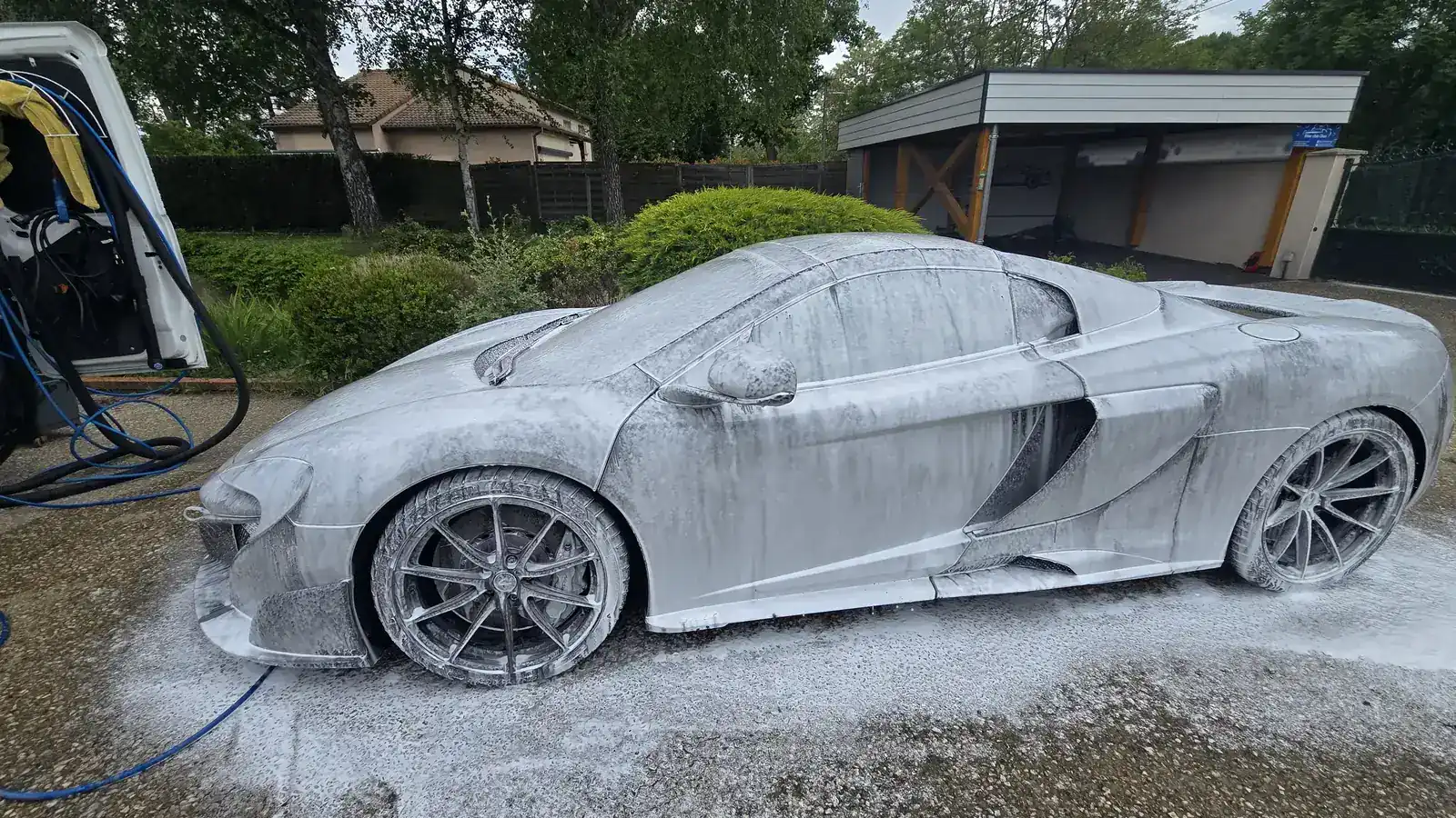 Voiture de sport recouverte de mousse de prélavage lors d'un lavage auto à domicile
